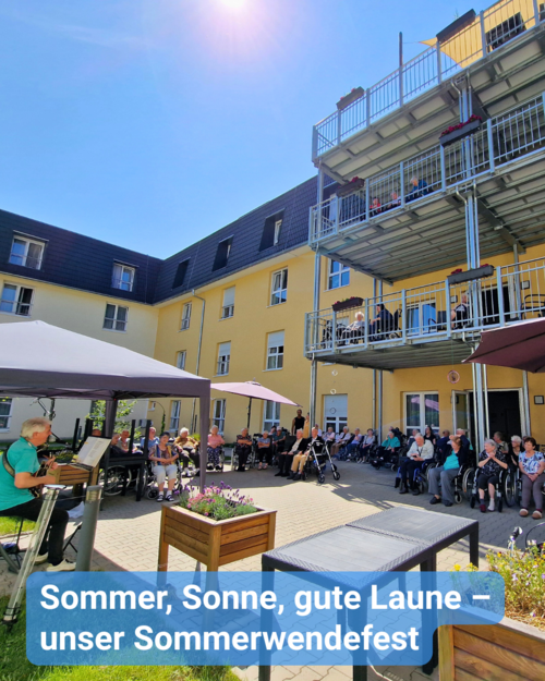 Außenbereich mit vielen Menschen vor gelbem Gebäude. Text: 'Sommer, Sonne, gute Laune – unser Sommerwendefest'.
